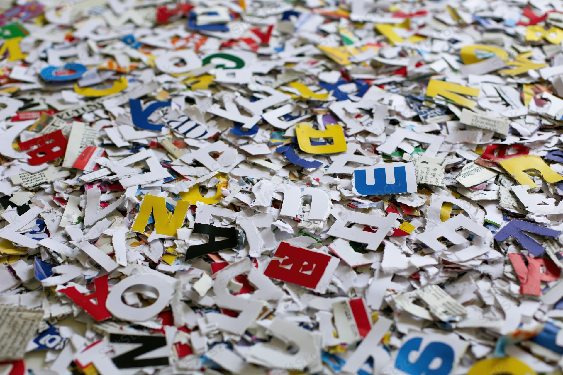 Scattered cut-out letters from magazine and newspaper pages covering a surface