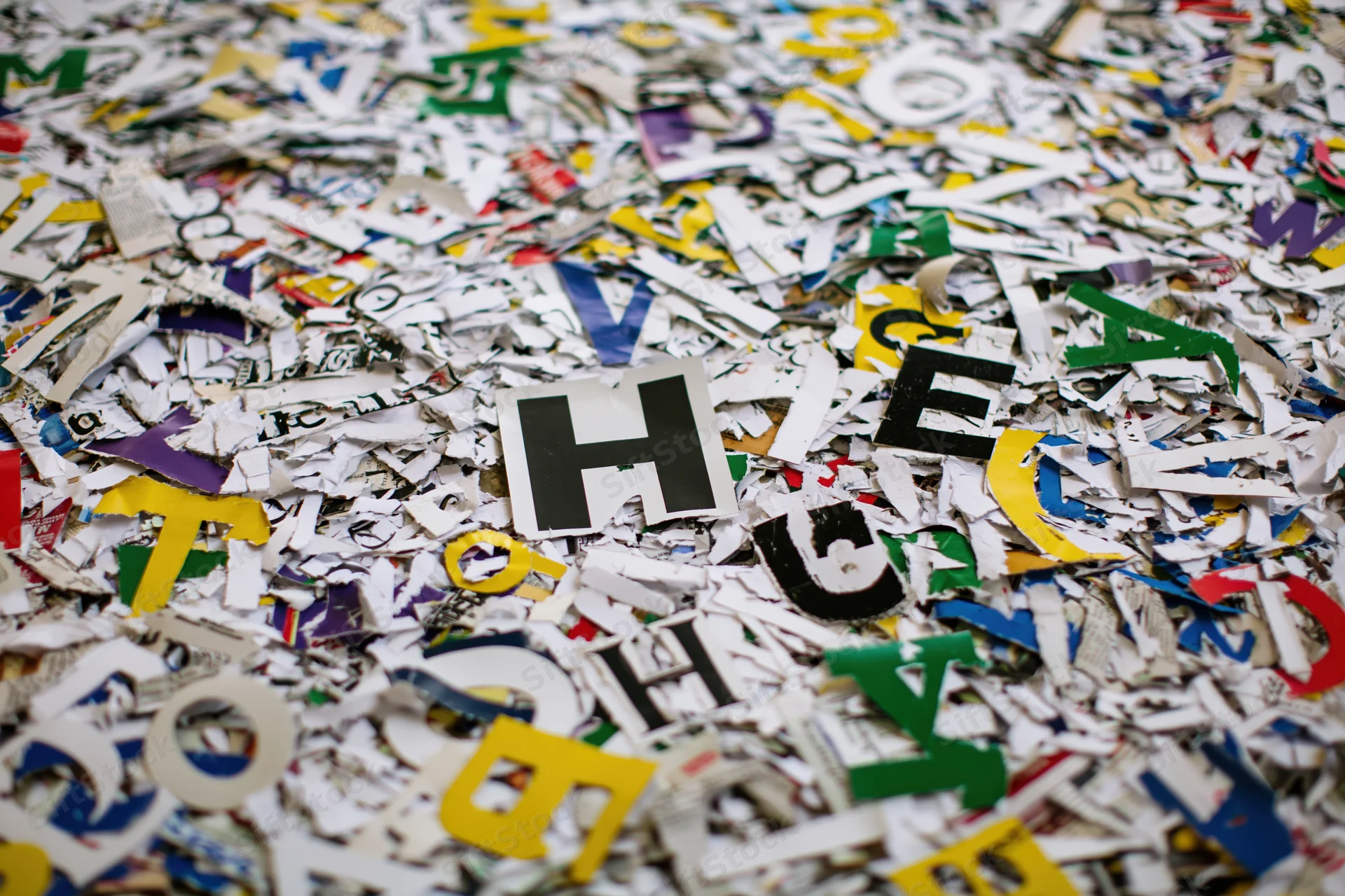 Scattered cutout letters from magazine and newspaper pages covering a surface