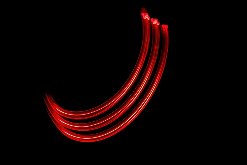 Red light trail forming a lowercase letter j against black background