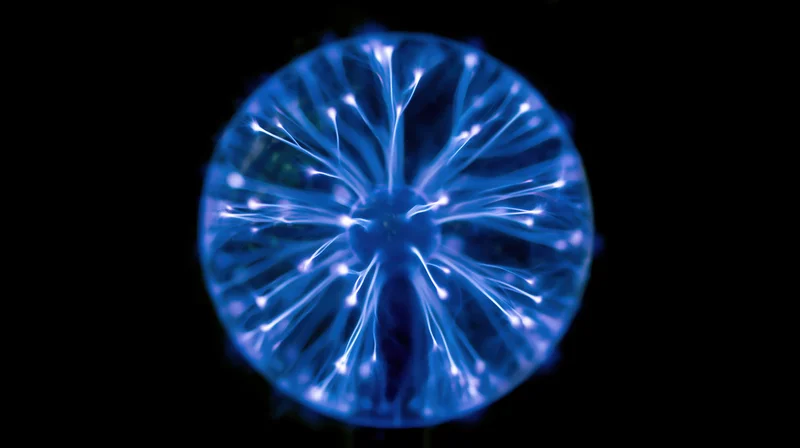 Glowing plasma ball with electric filaments radiating from center against dark background