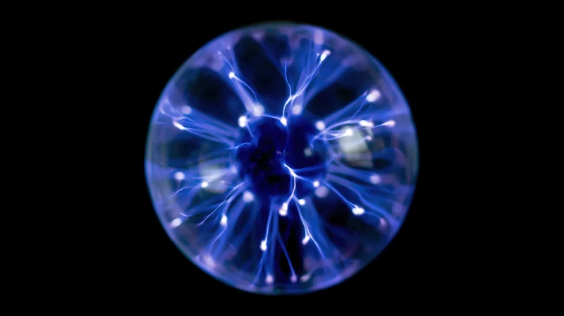 Glowing plasma ball with electric filaments against black background
