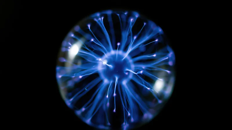 Glowing plasma ball with blue electric filaments against dark background