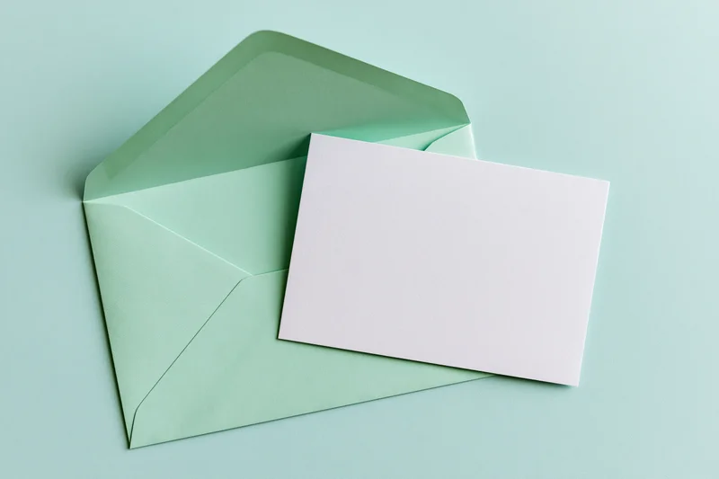 Mint green envelope open with blank white card on pastel surface