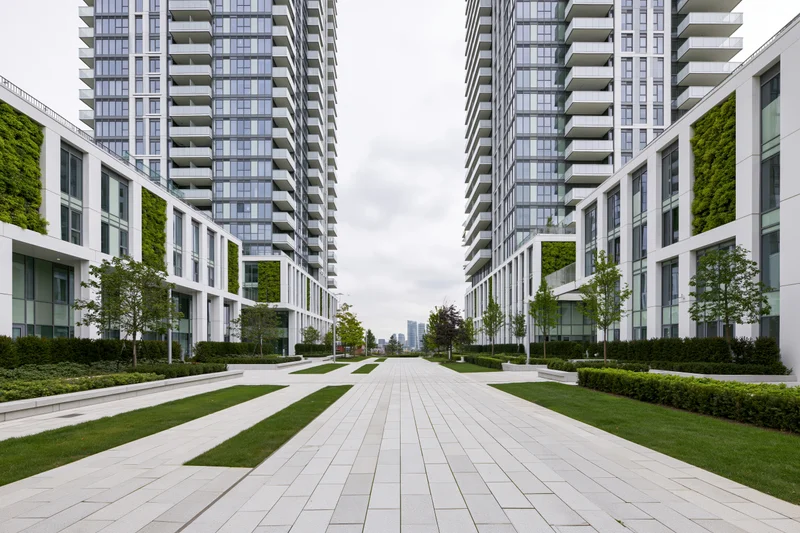 Modern mixed-use development courtyard with green walls and paved walkway between high-rise buildings
