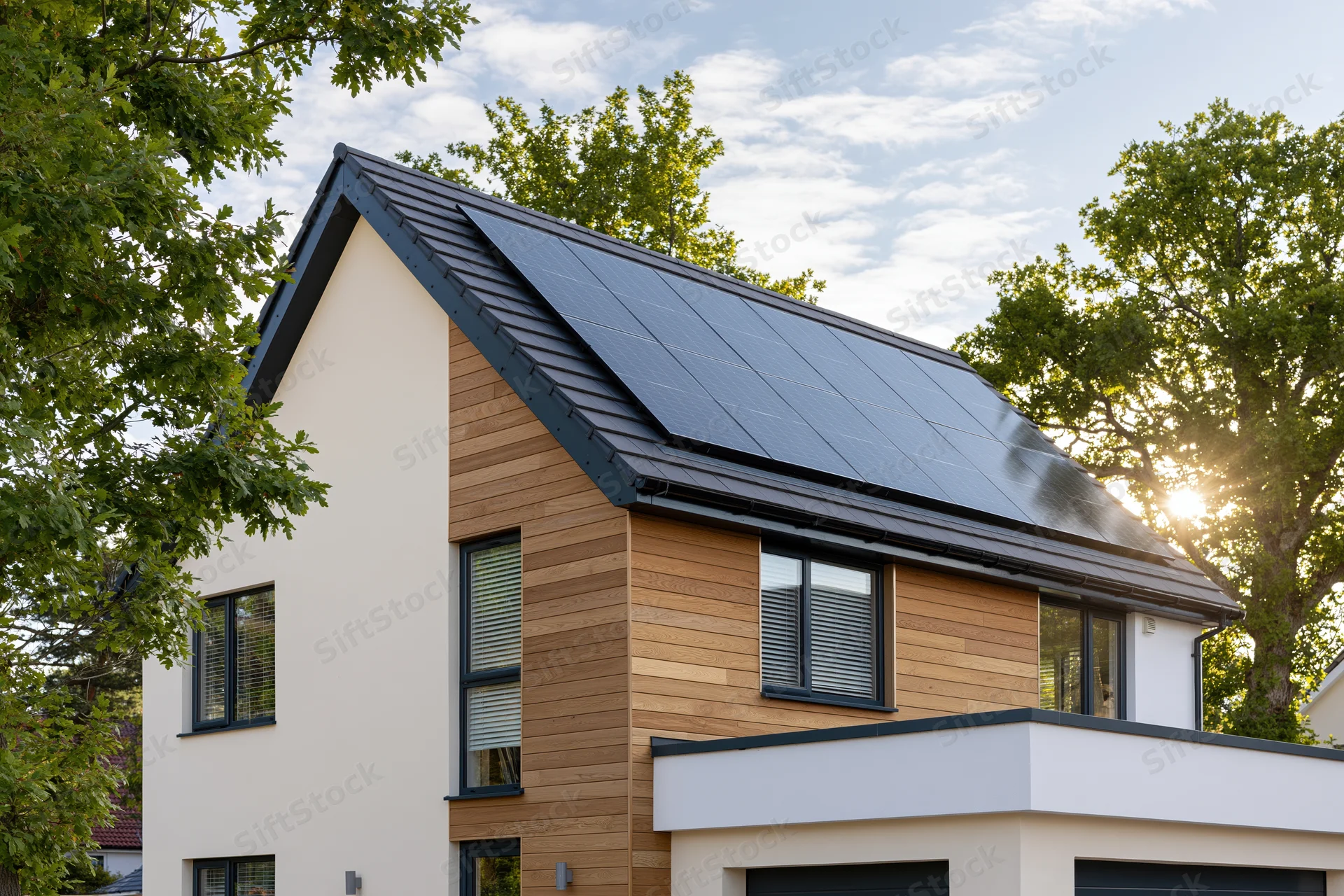 Modern suburban house with solar panels on the roof surrounded by trees