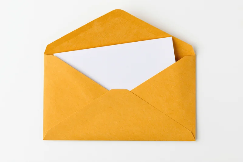 Open golden yellow paper envelope with blank white card inside, flat lay on white background