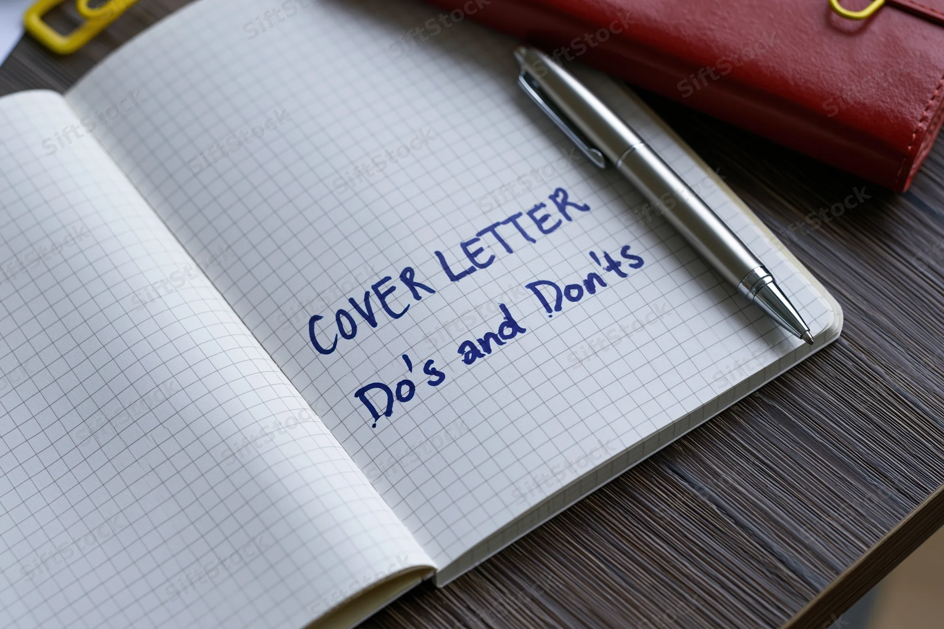 Open grid-lined notebook with handwritten cover letter do's and don'ts on dark wooden desk with pen and red wallet