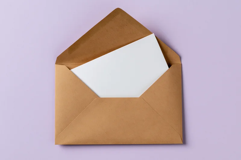 Open kraft paper envelope with blank white card inside on purple background