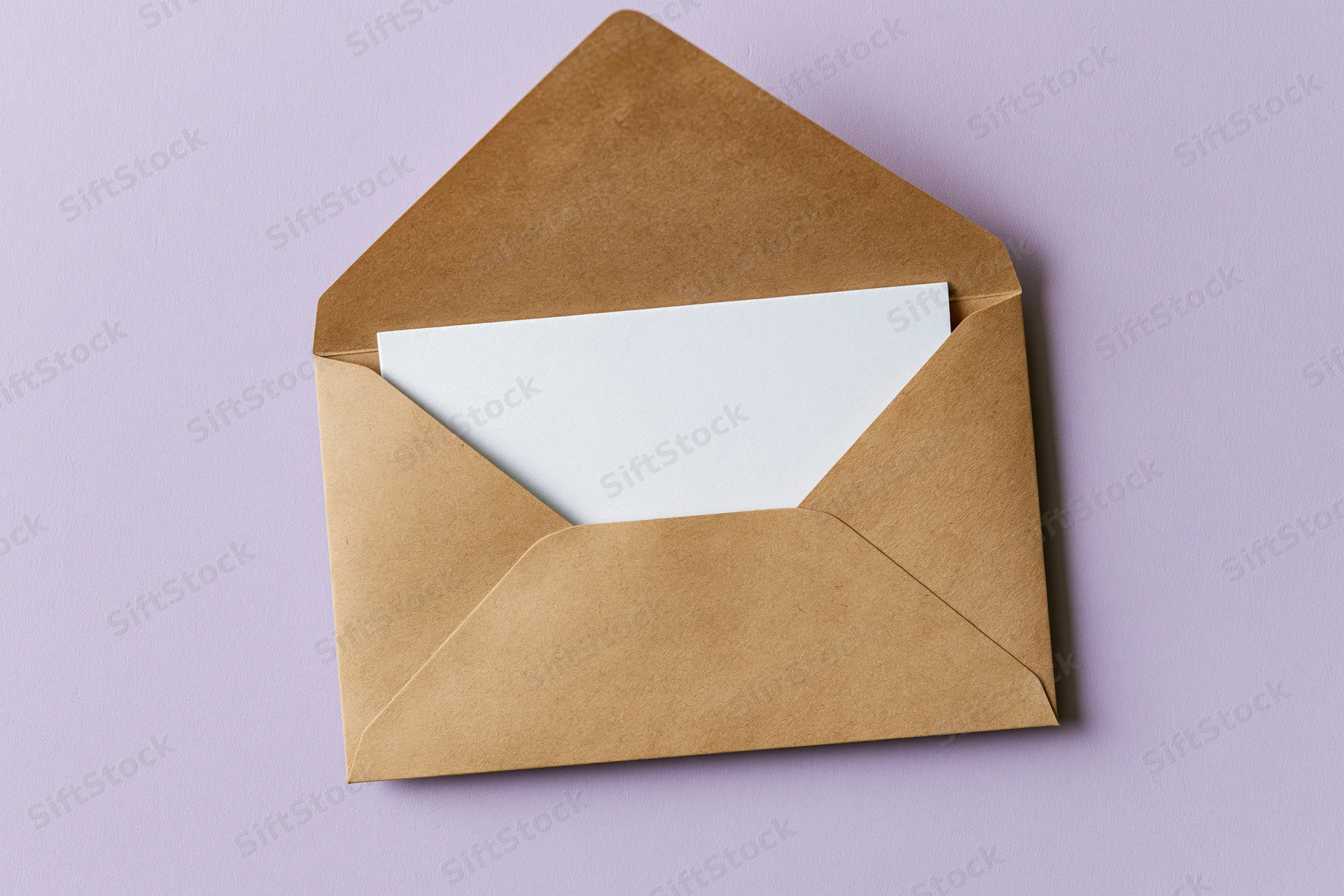Open kraft paper envelope with blank white card on purple background