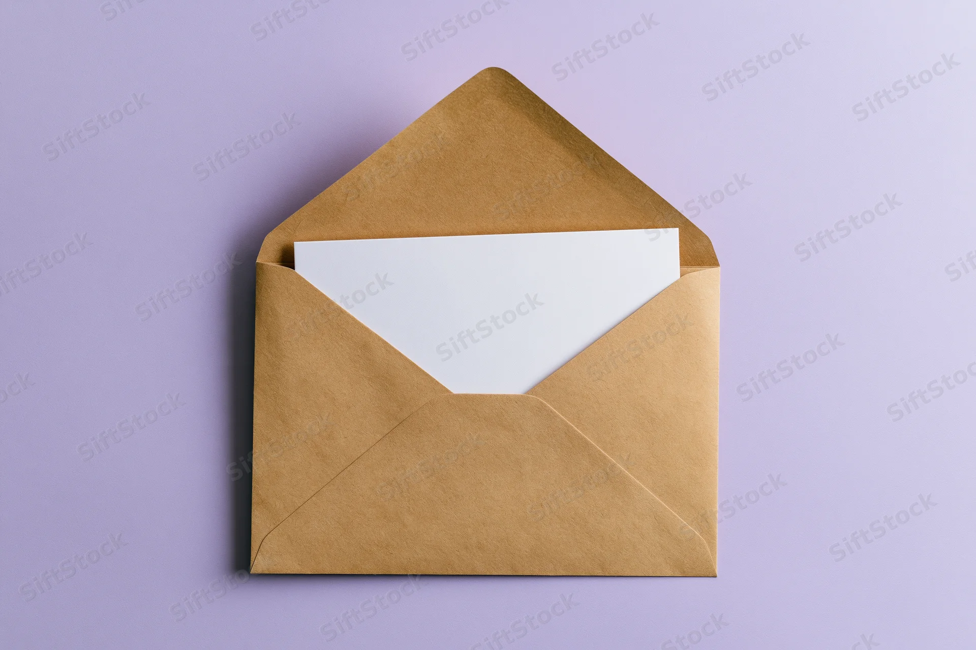 Open kraft paper envelope with blank white card inside on lavender background