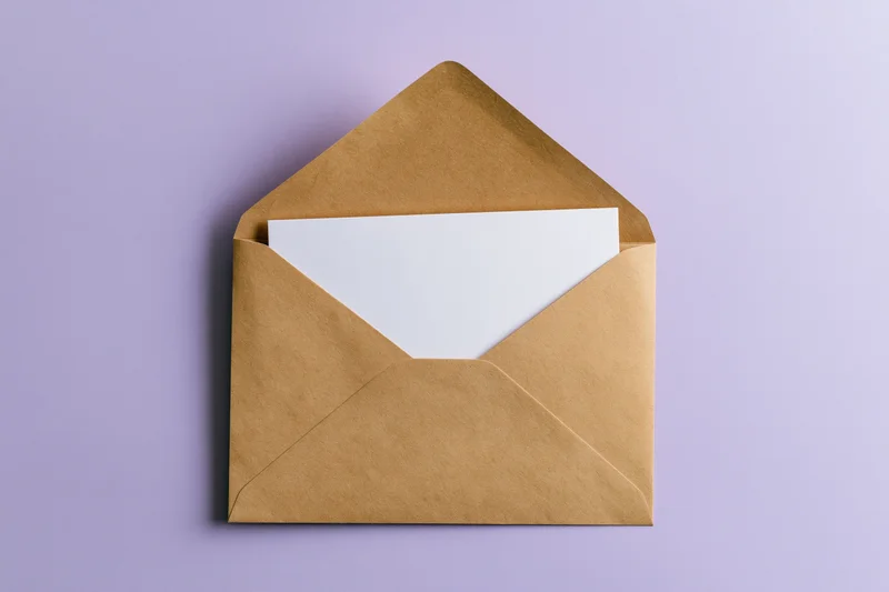 Open kraft paper envelope with blank white card inside on lavender background