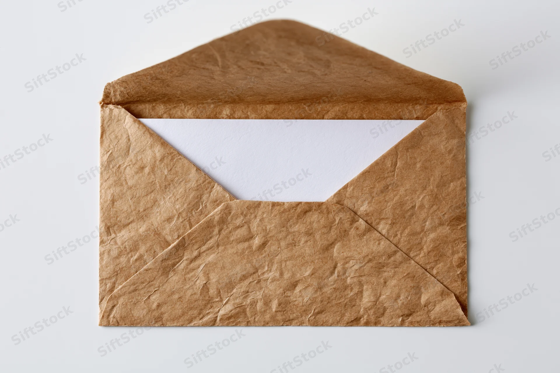 Open kraft paper envelope with blank white card inside on white background