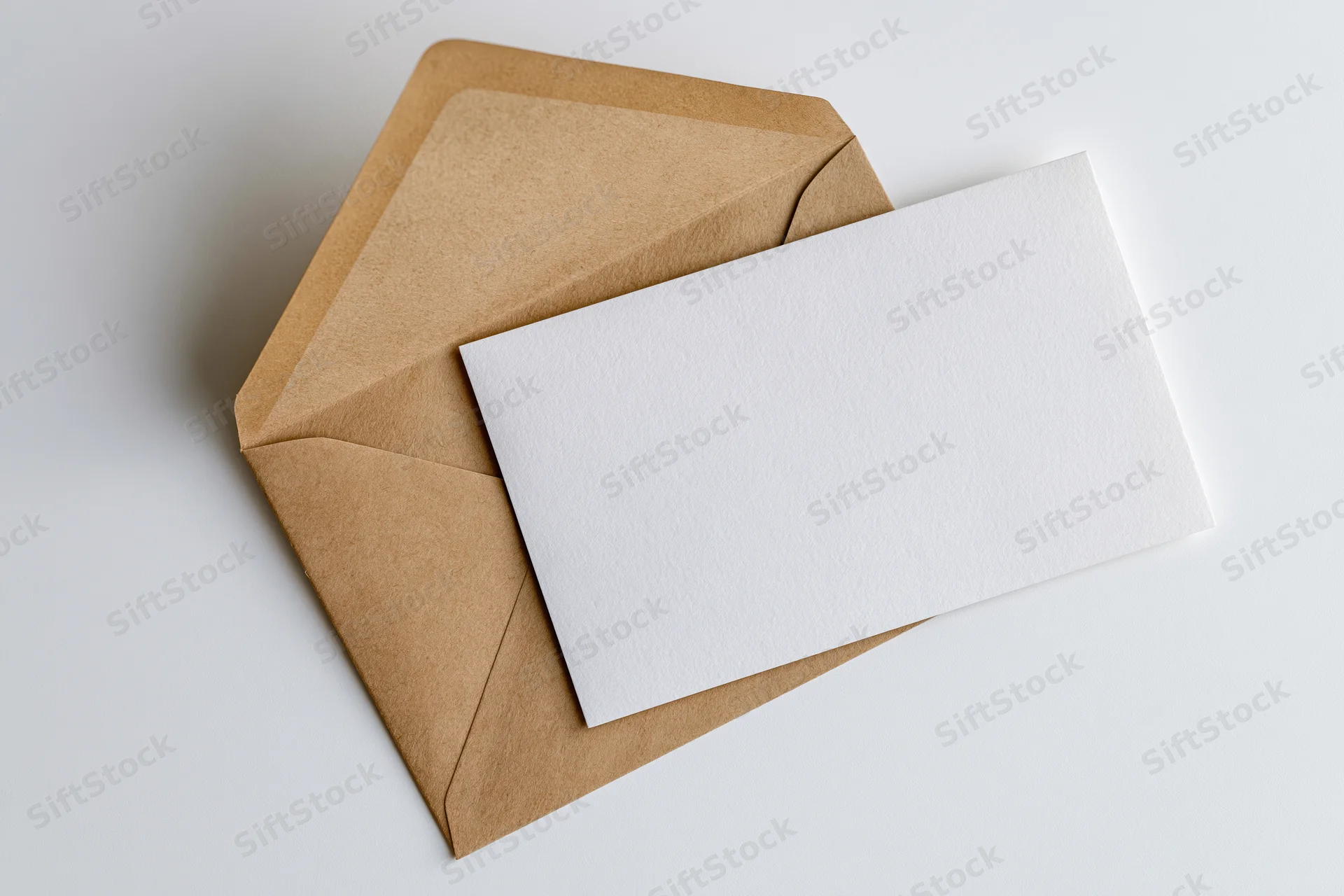 Open kraft paper envelope with blank white card resting on white surface