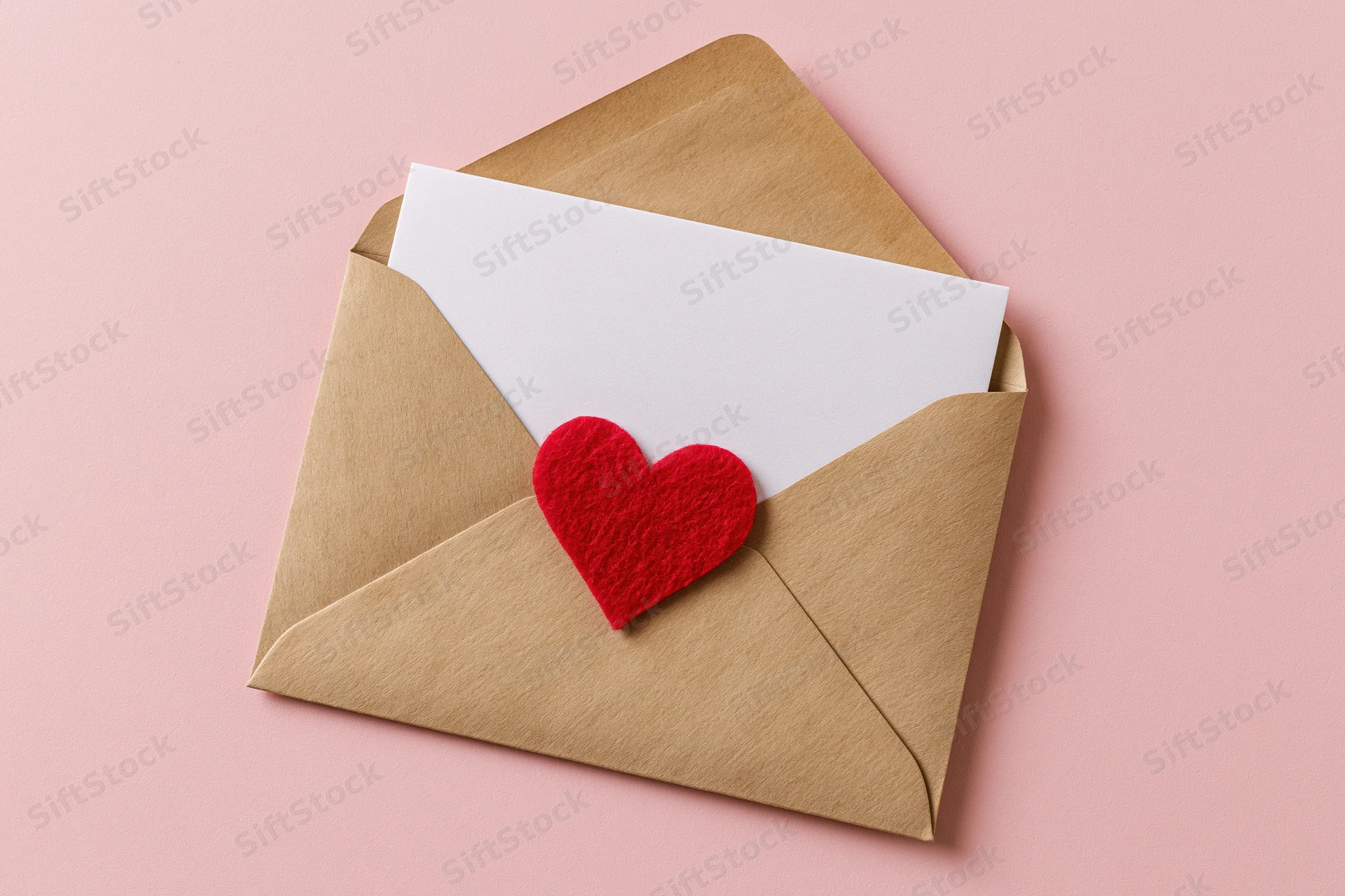 Open kraft paper envelope with red felt heart sticker on pink background