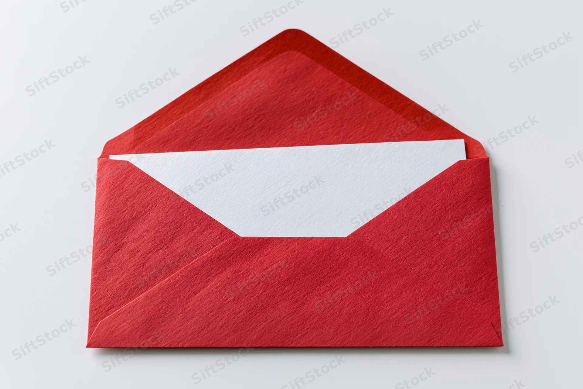 Open red paper envelope with blank white card partially pulled out on white background