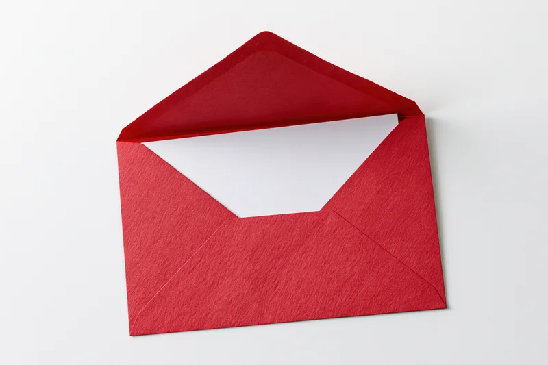 Open red paper envelope with blank white card inside on white background