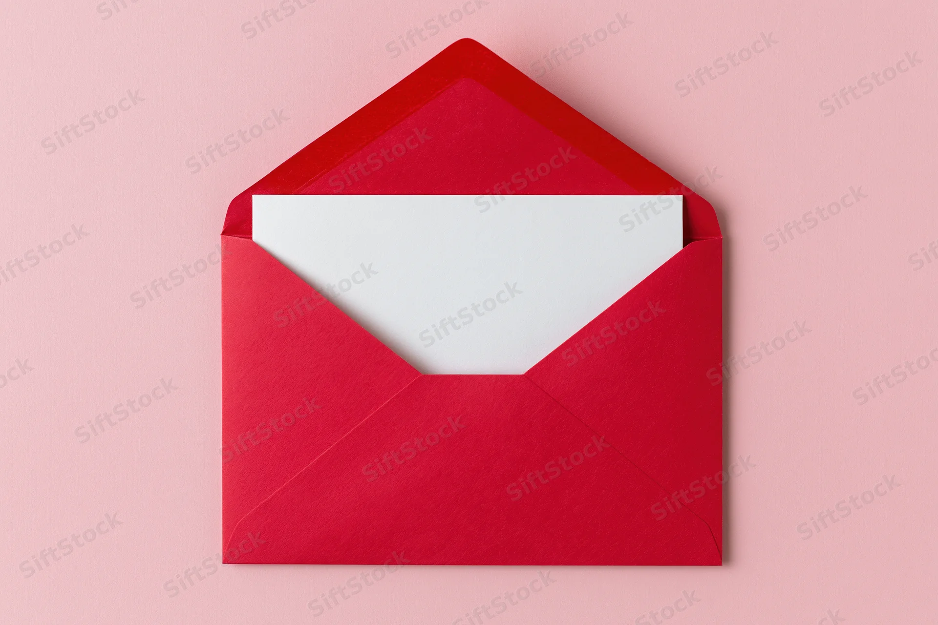 Open red paper envelope with blank white card inside on pink background