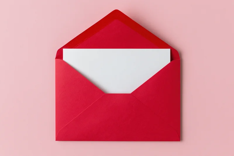 Open red paper envelope with blank white card inside on pink background