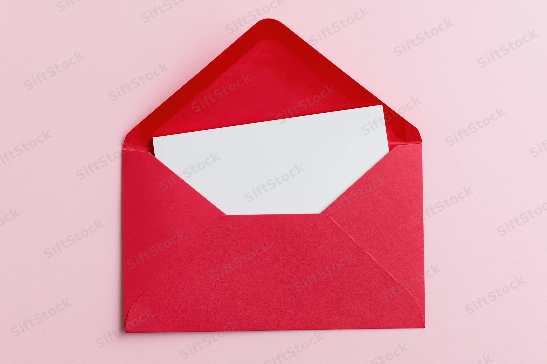 Open red paper envelope with blank white card inside on pink background