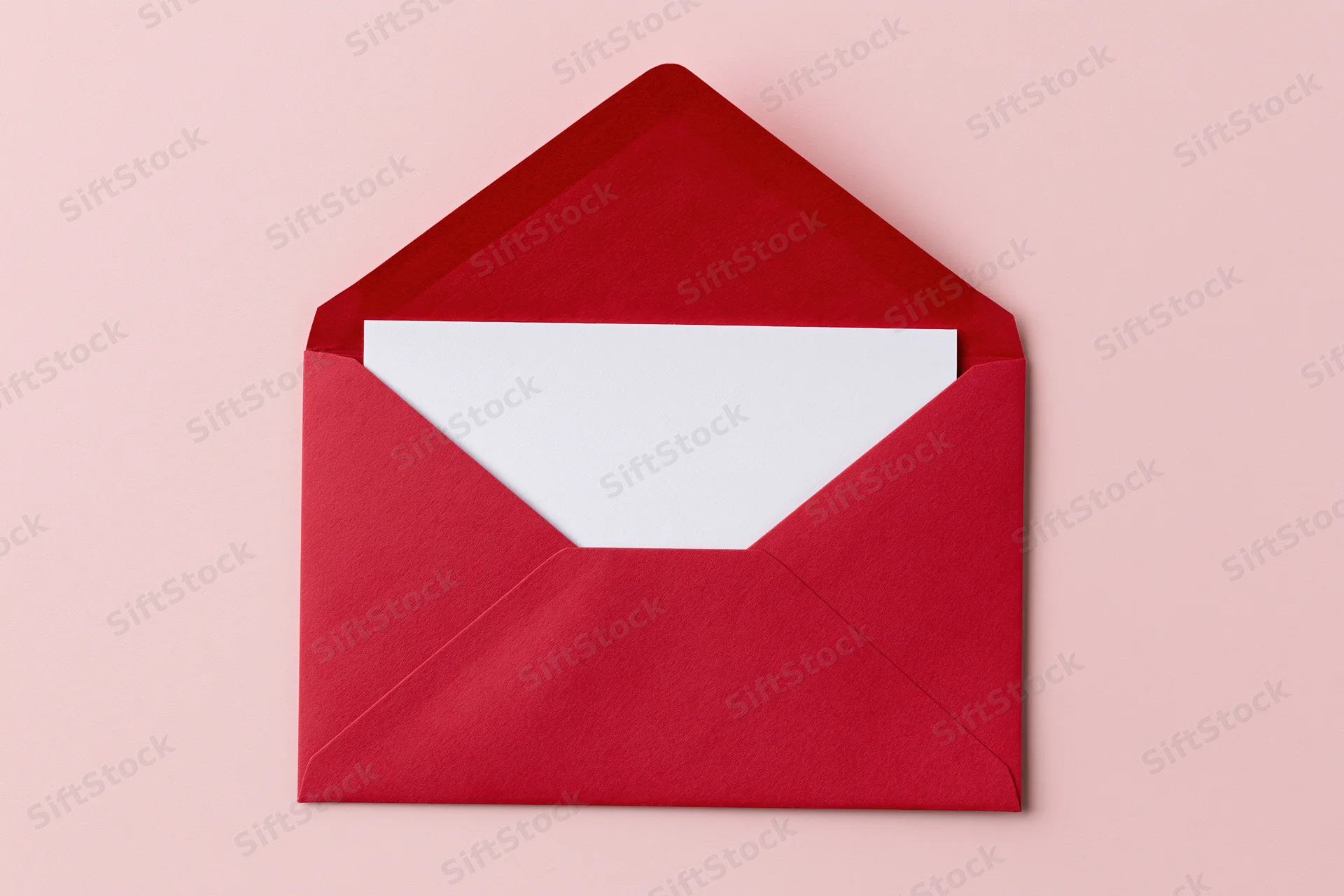 Open red paper envelope with blank white card inside on pink background