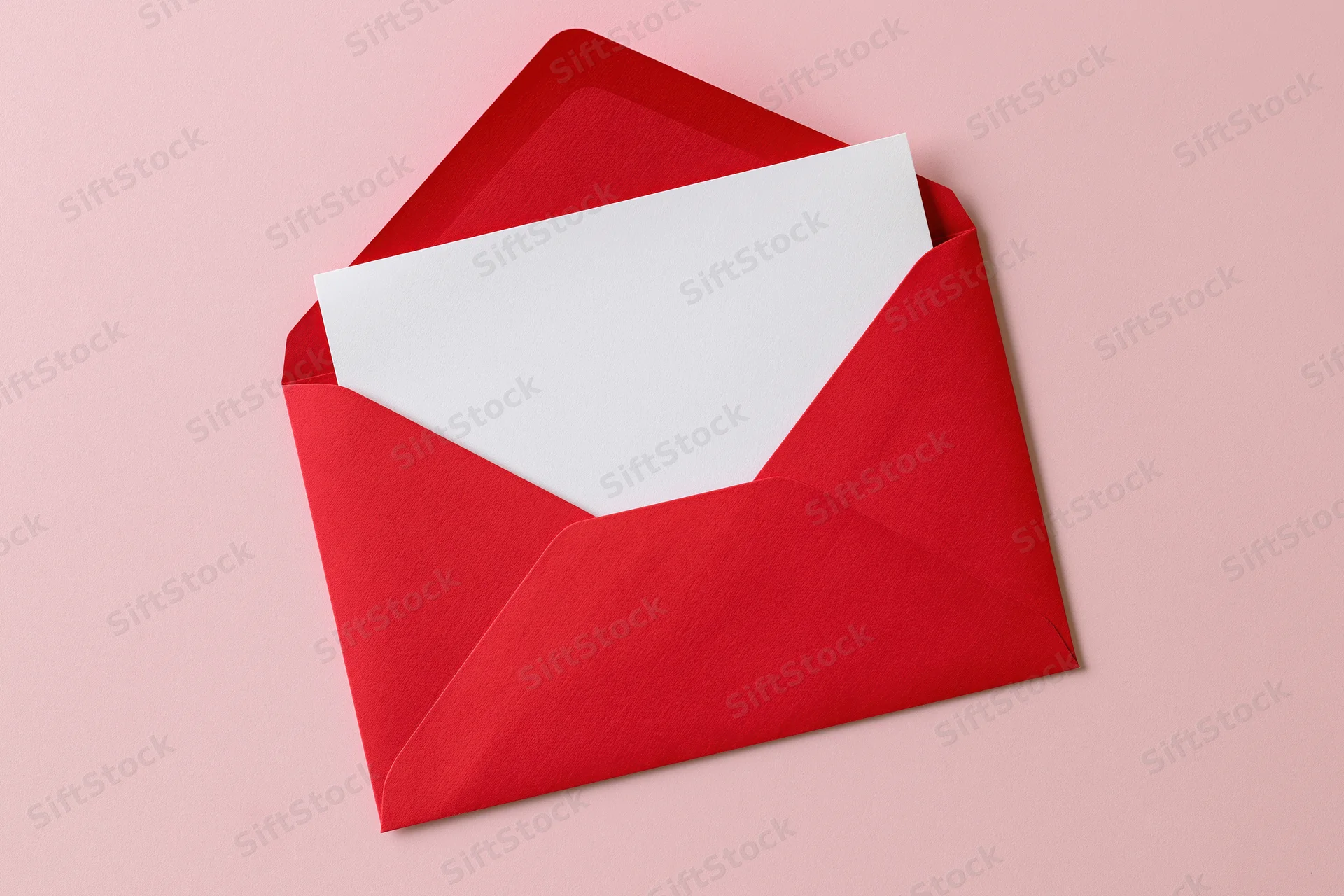 Open red paper envelope with blank white card inside on pink surface