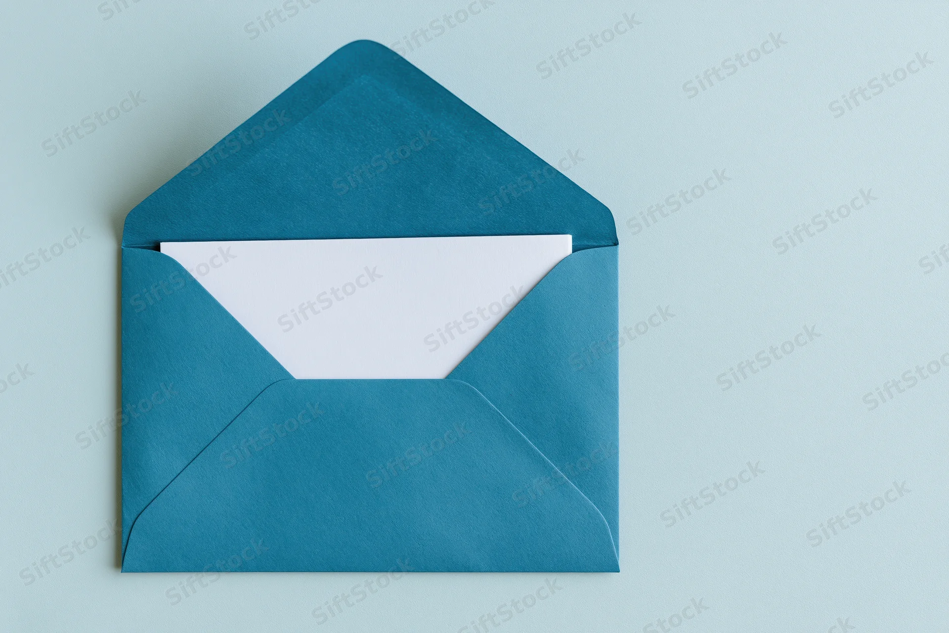 Open teal paper envelope with blank white card inside on light blue surface