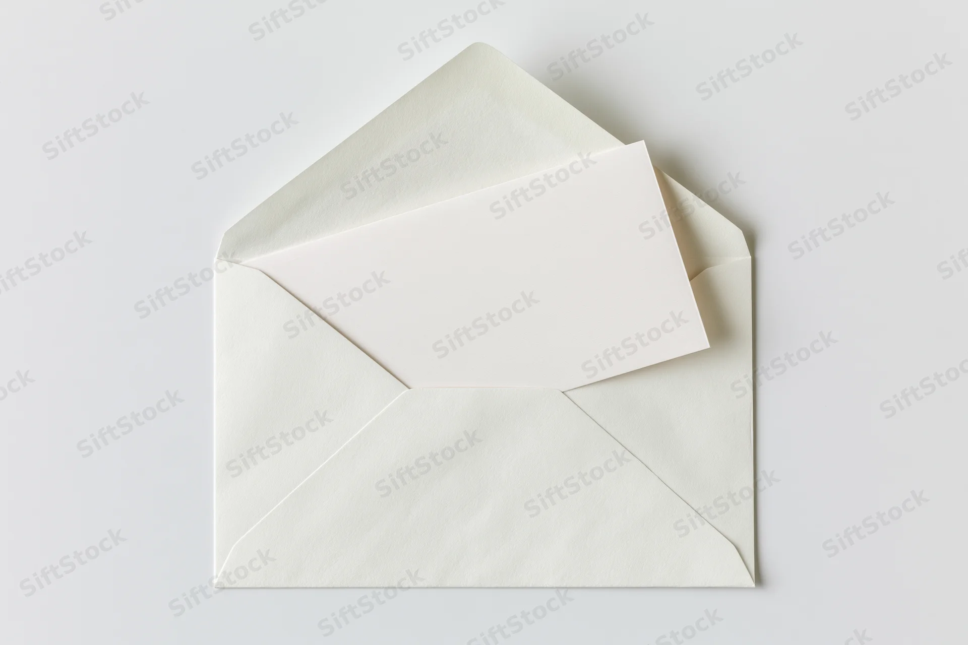 Open white paper envelope with blank card partially pulled out on plain surface