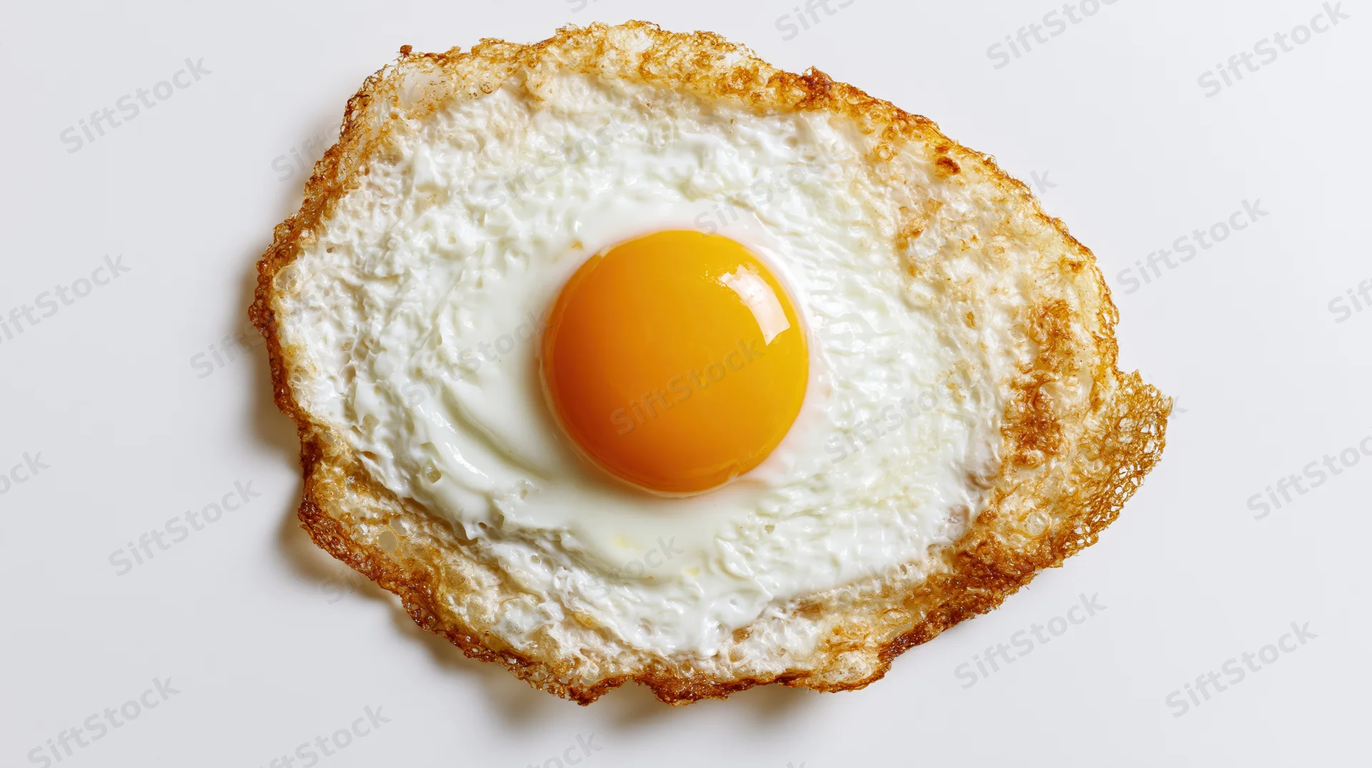 Single fried egg viewed from above on a plain white surface