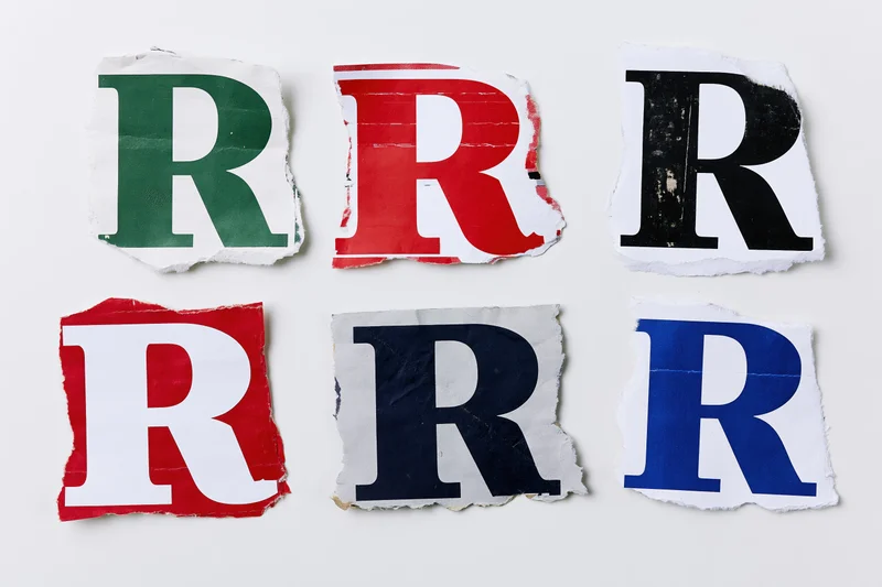 Six torn paper fragments each showing a letter r in different colors arranged in two rows on a white surface