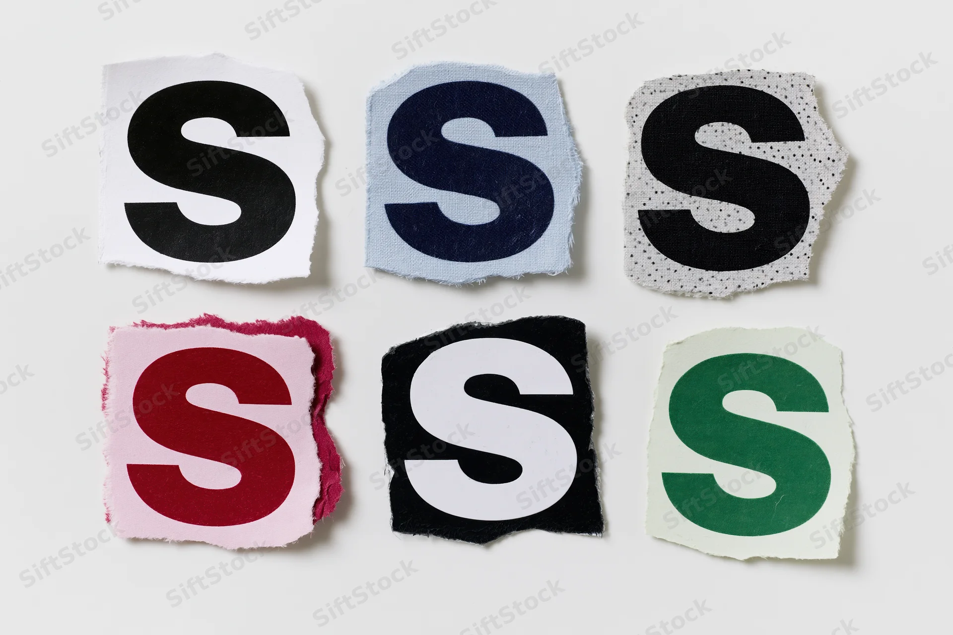 Six torn paper cutouts of the letter s arranged in a two by three grid on a white surface