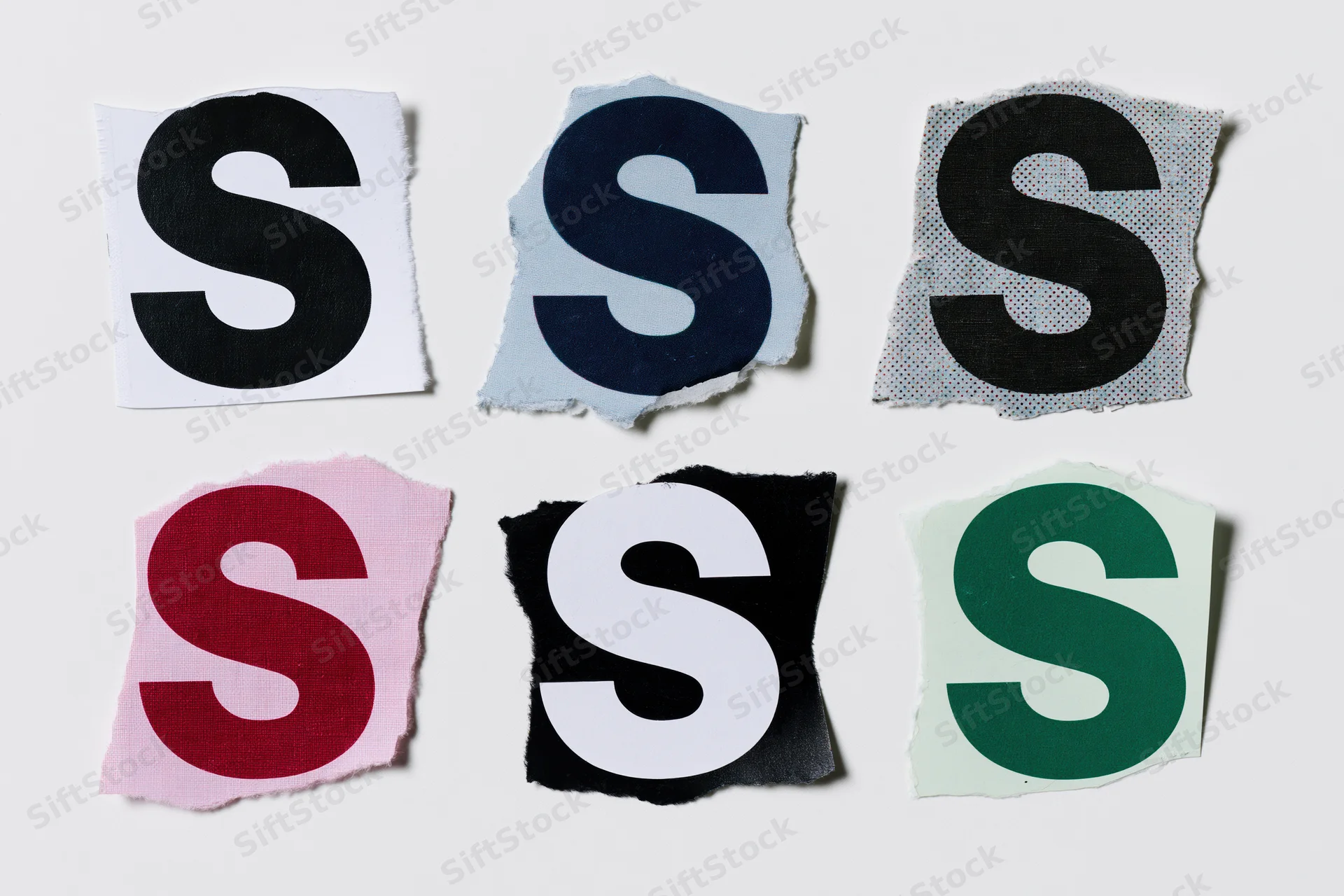 Six torn paper cutouts of the letter s arranged in a grid on a white surface
