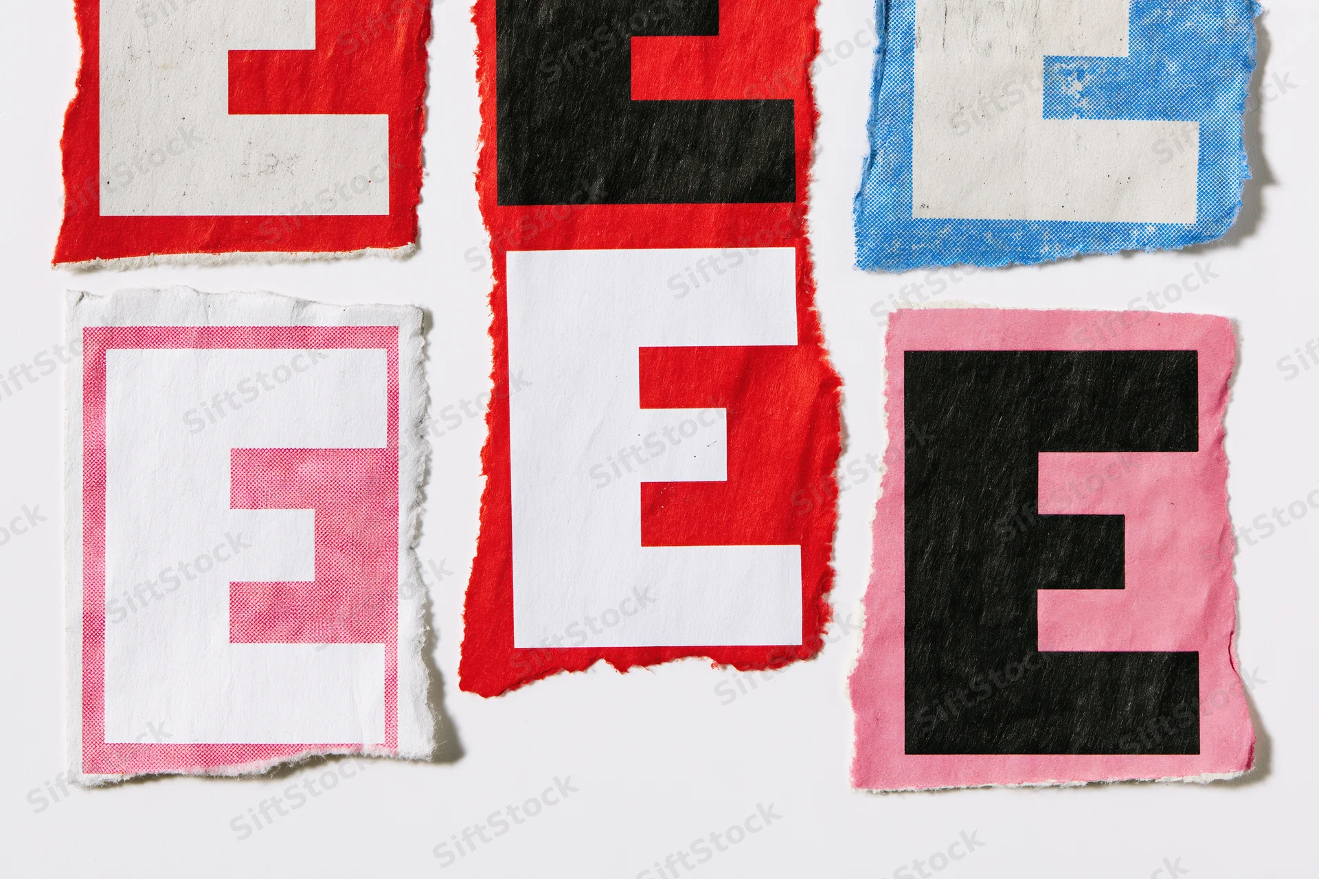 Six torn paper cutouts of the letter e in various colors arranged on a white surface