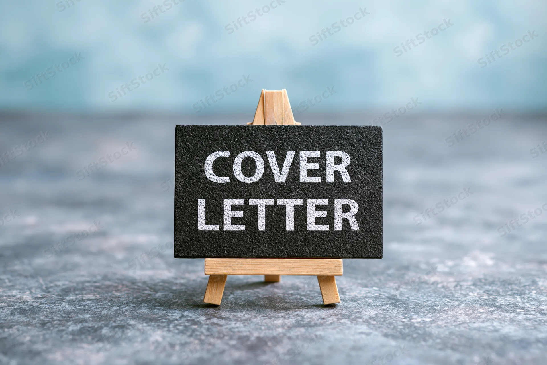 Black chalkboard sign reading cover letter on wooden easel stand on textured surface