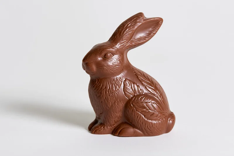 Milk chocolate easter bunny figurine sitting upright on white surface