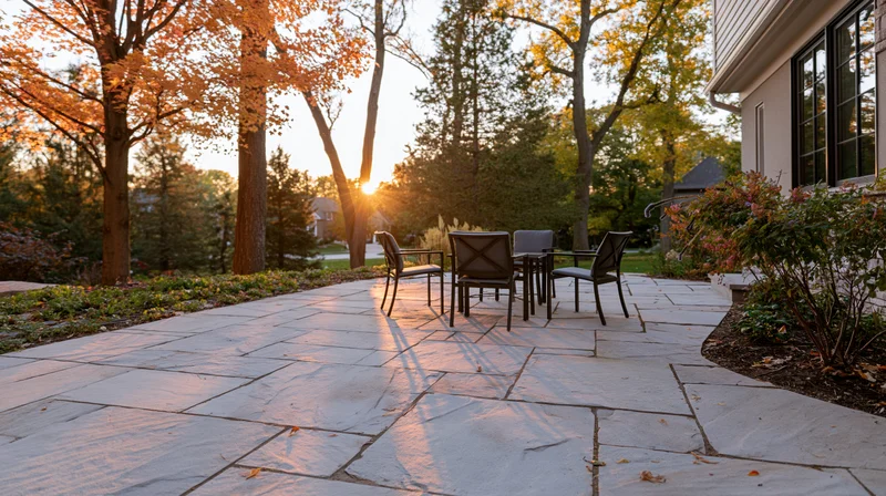 Stone patio with metal furniture in suburban backyard at golden hour during autumn