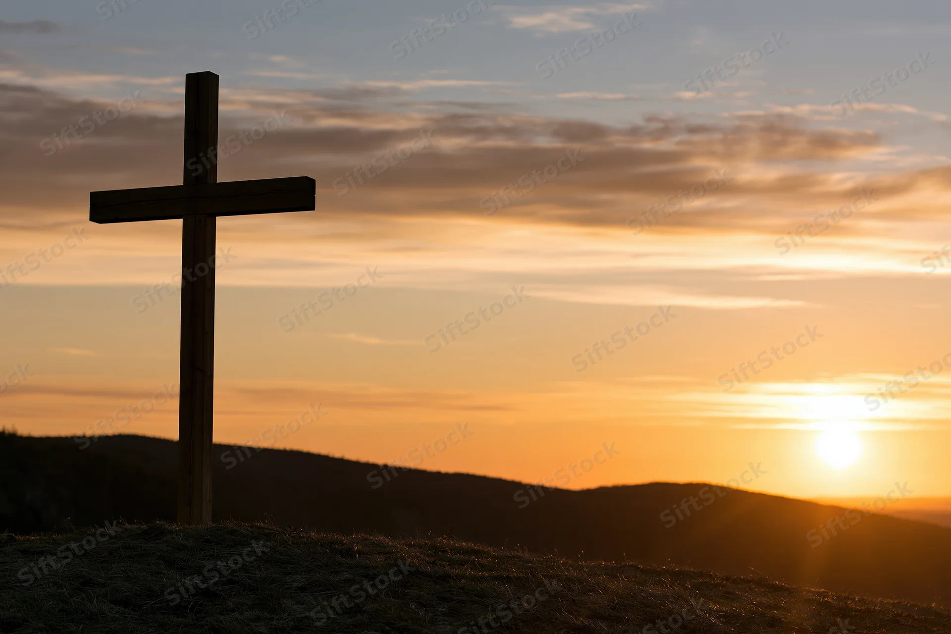 Wooden christian cross silhouetted on a hilltop at sunset