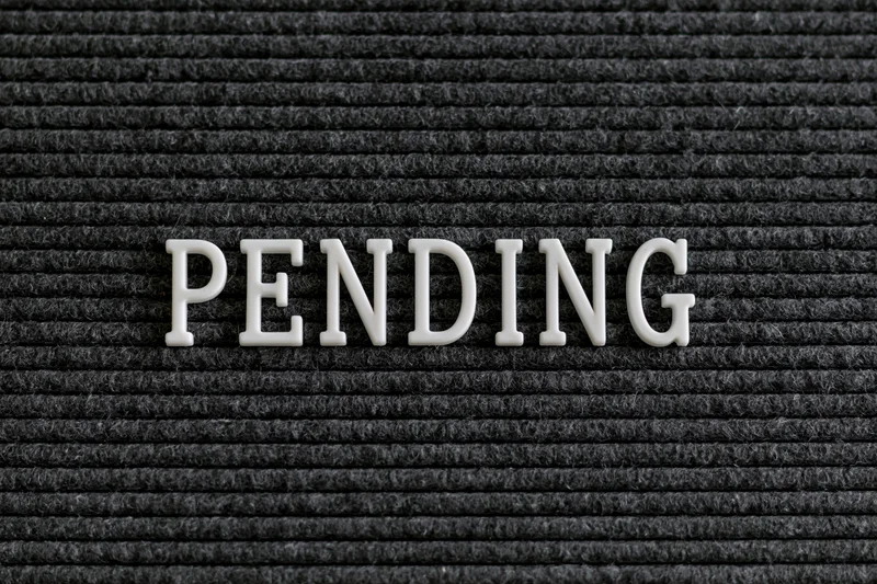 White plastic letters spelling pending on a black ribbed fabric surface