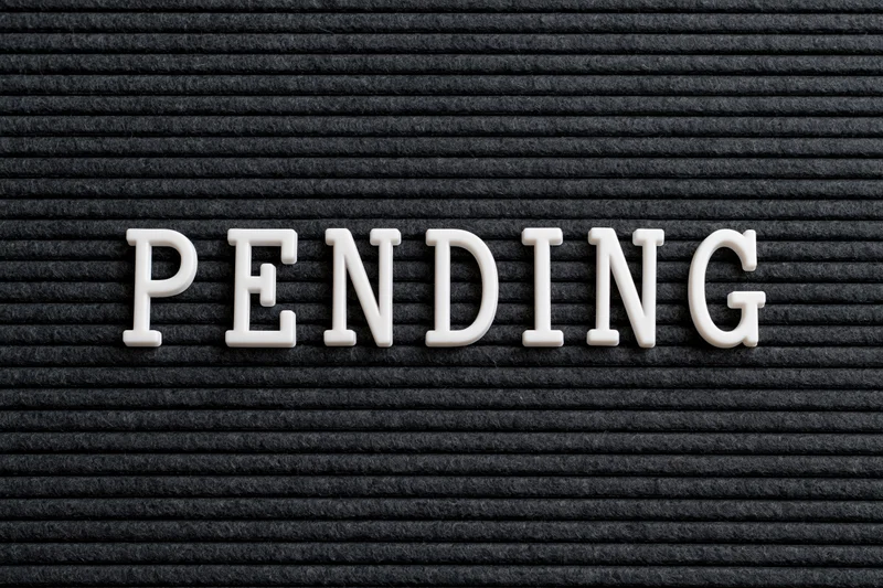 The word pending spelled in white plastic letters on a black textured board