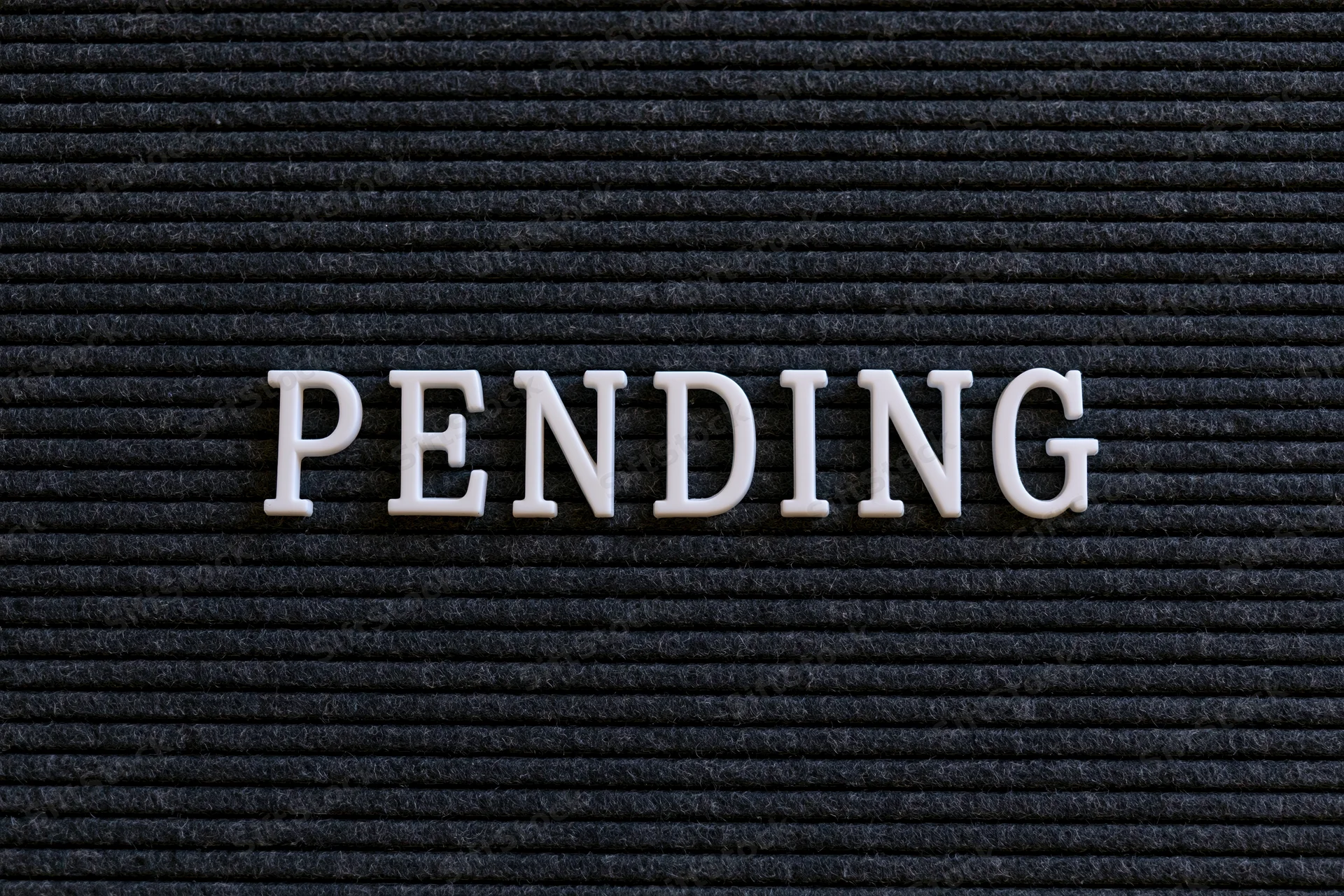 The word pending spelled in white plastic letters on a black textured board