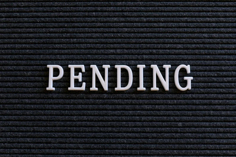 The word pending spelled in white plastic letters on a black textured board