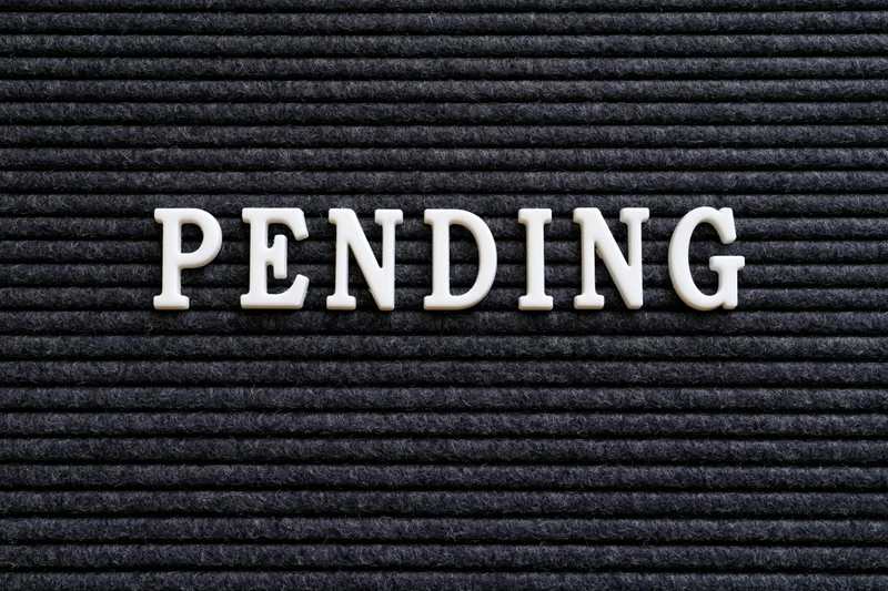 White plastic letters spelling pending on a black ribbed surface