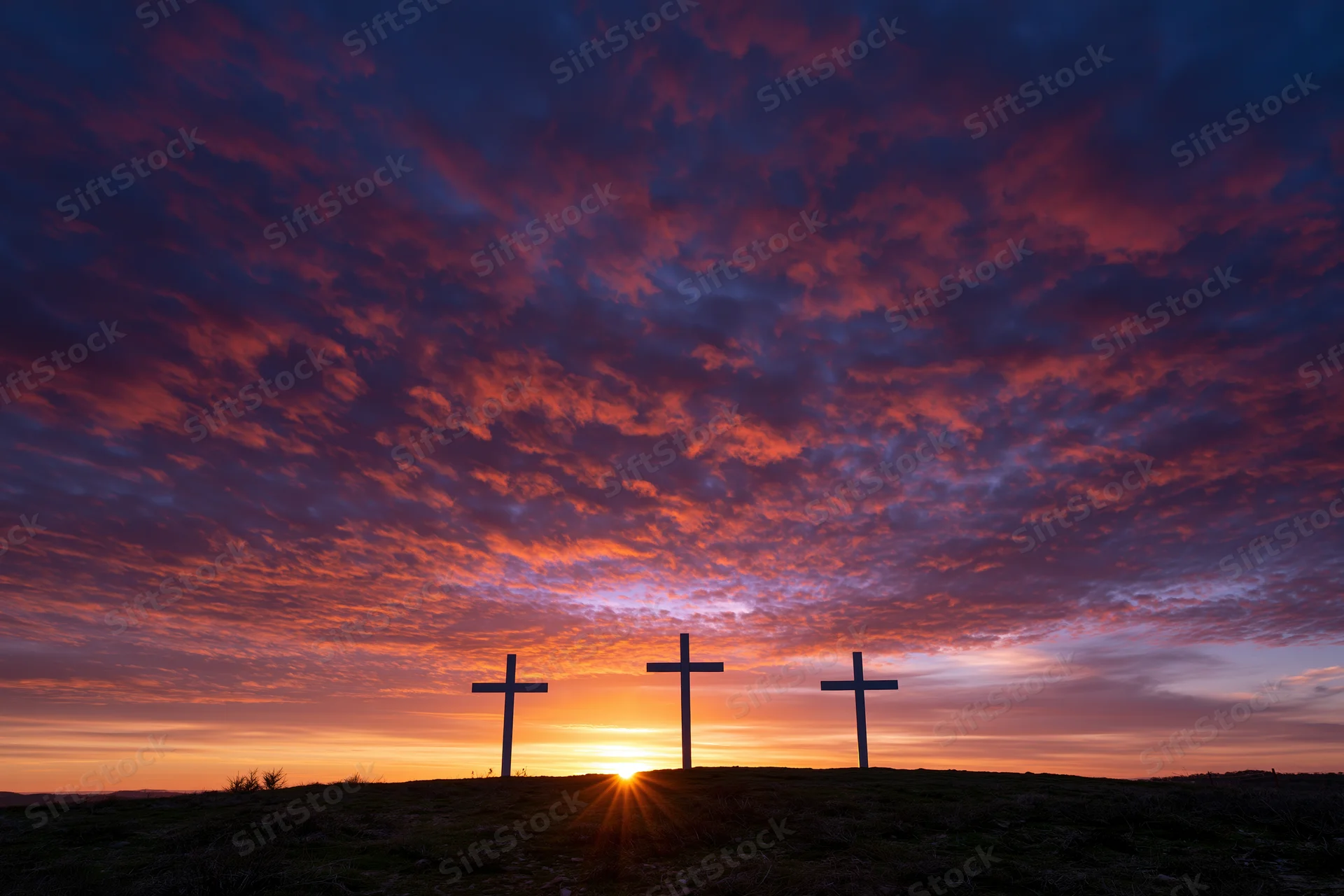 Three christian crosses silhouetted on a hilltop at sunset