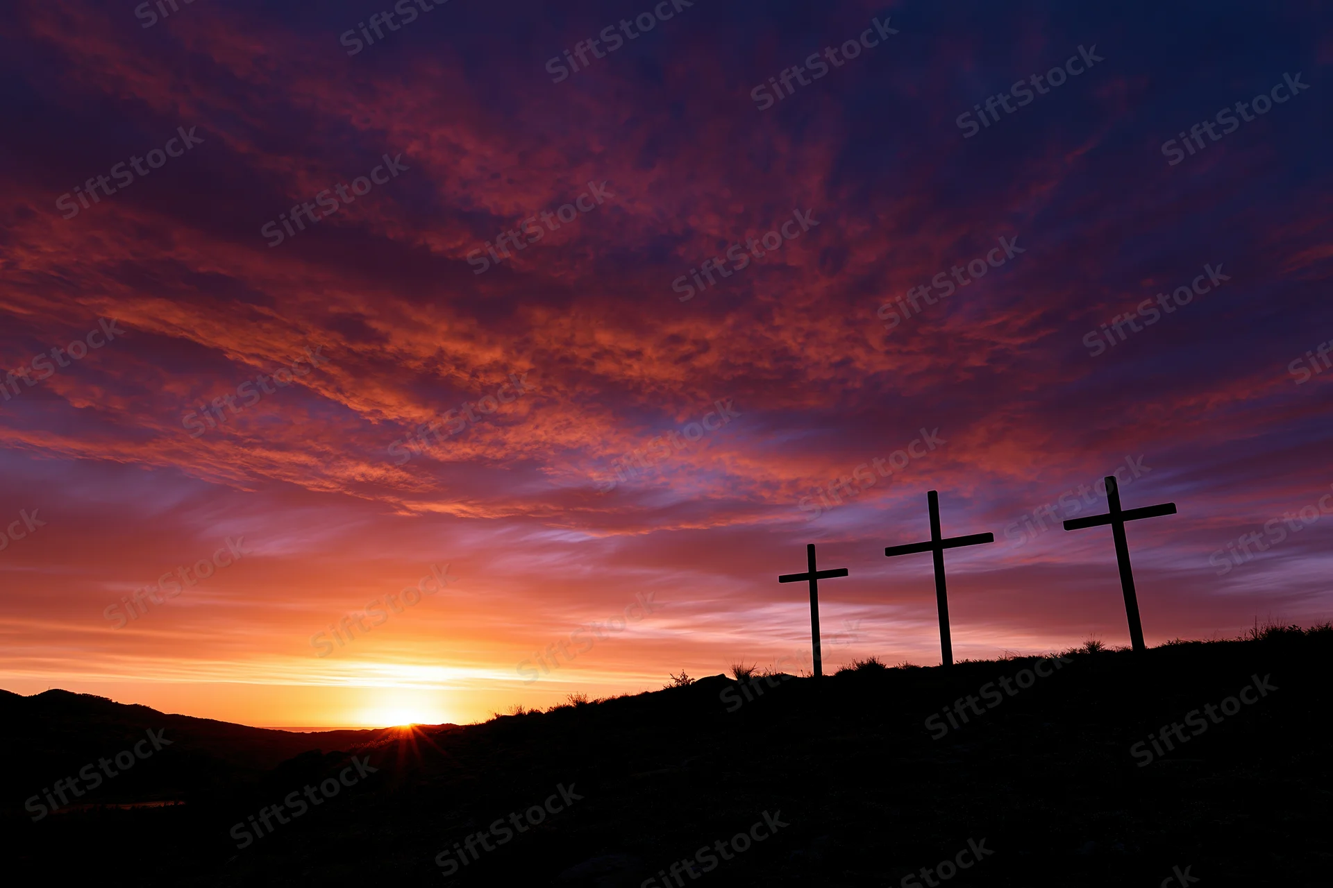 Three christian crosses silhouetted on a dark hilltop at sunset