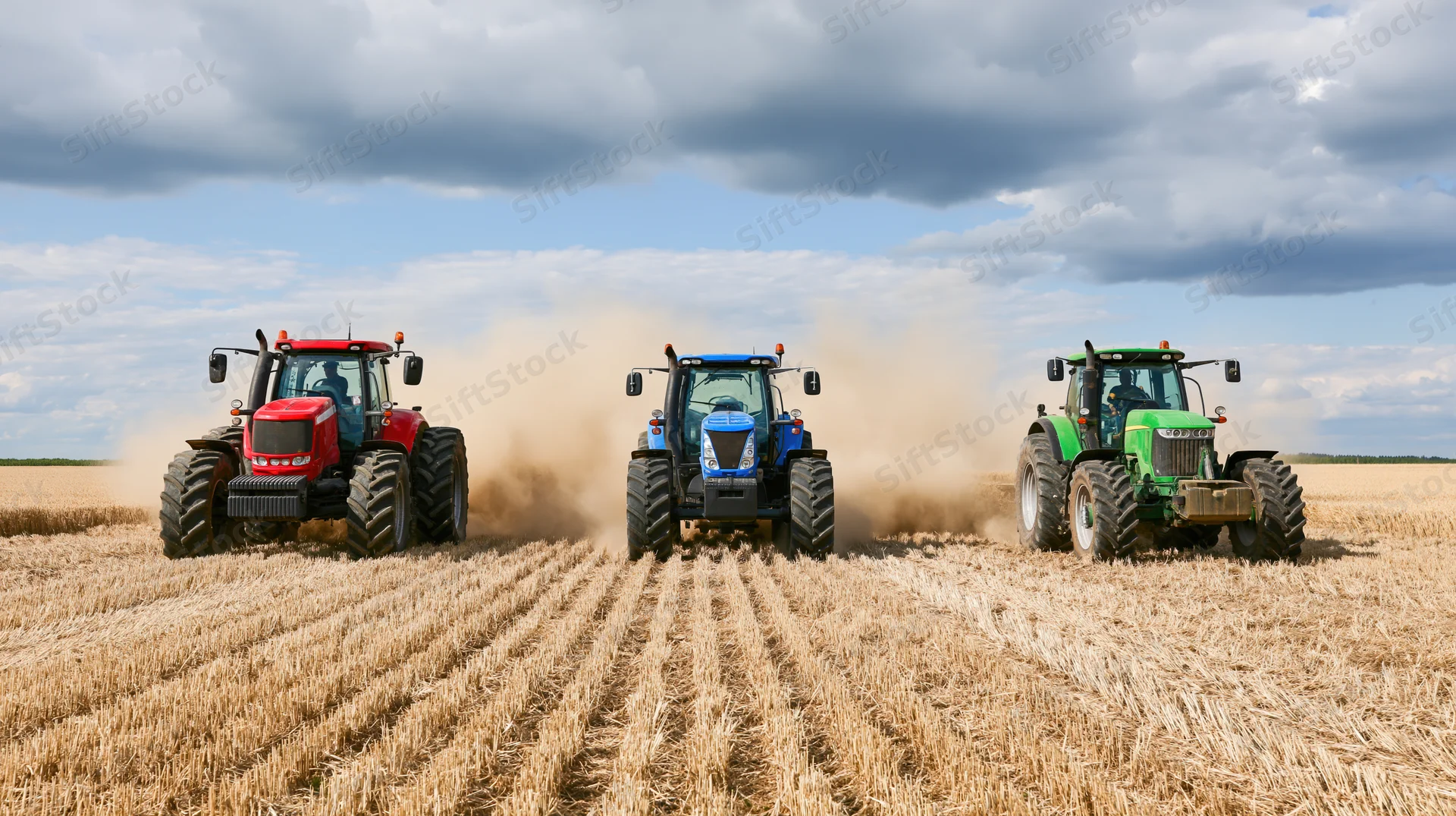 Three tractors driving side by side in a harvested field under cloudy sky