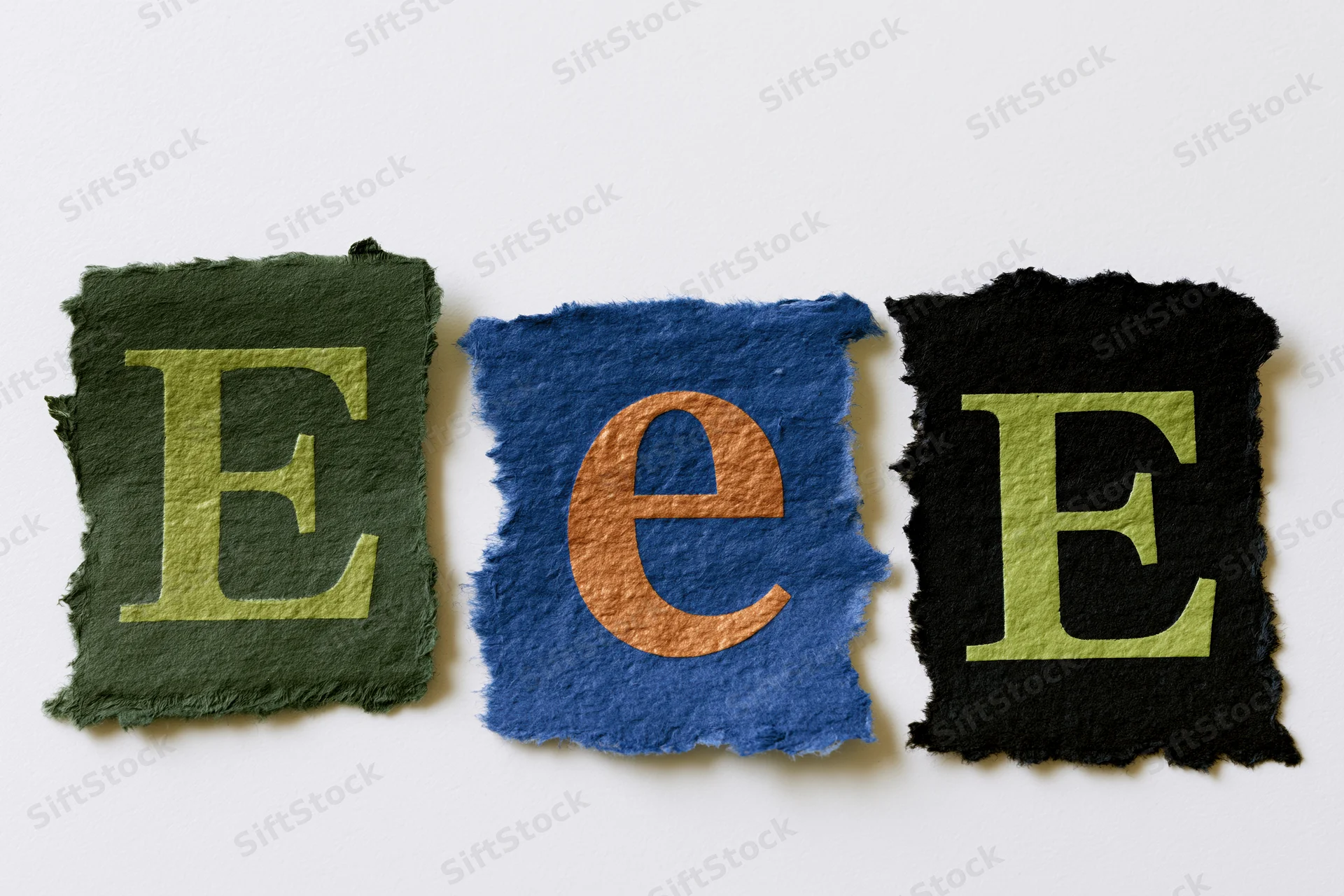 Three torn paper scraps with letters e and E arranged in a row on white background