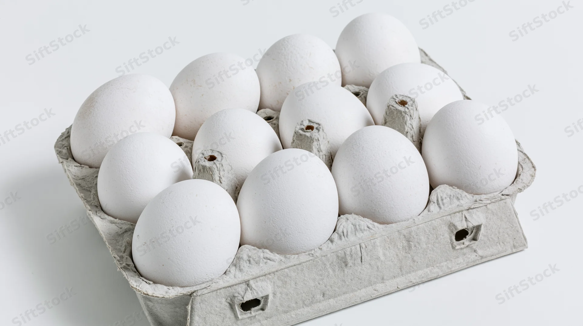 Twelve white eggs arranged in an open gray cardboard carton on a plain white surface