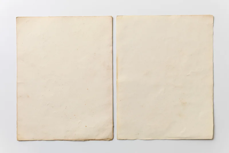 Two aged blank paper sheets laid flat side by side on white background