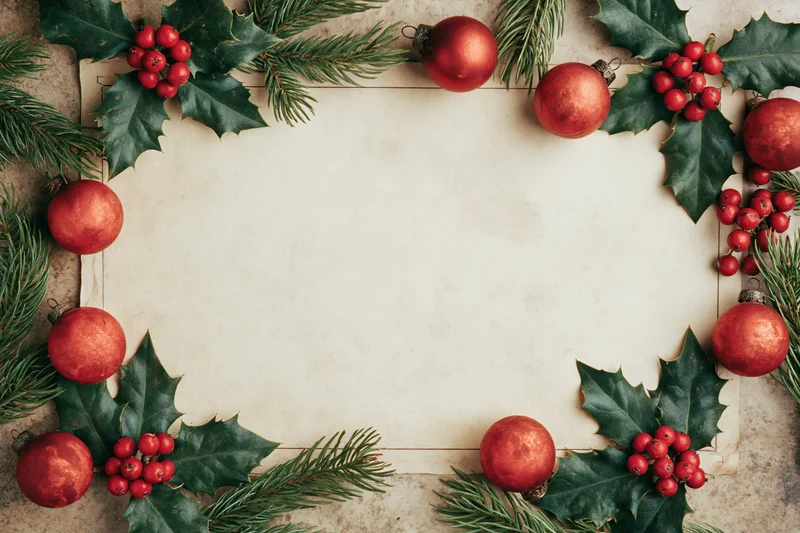 Vintage christmas card border with holly leaves and red ornaments framing a blank paper center