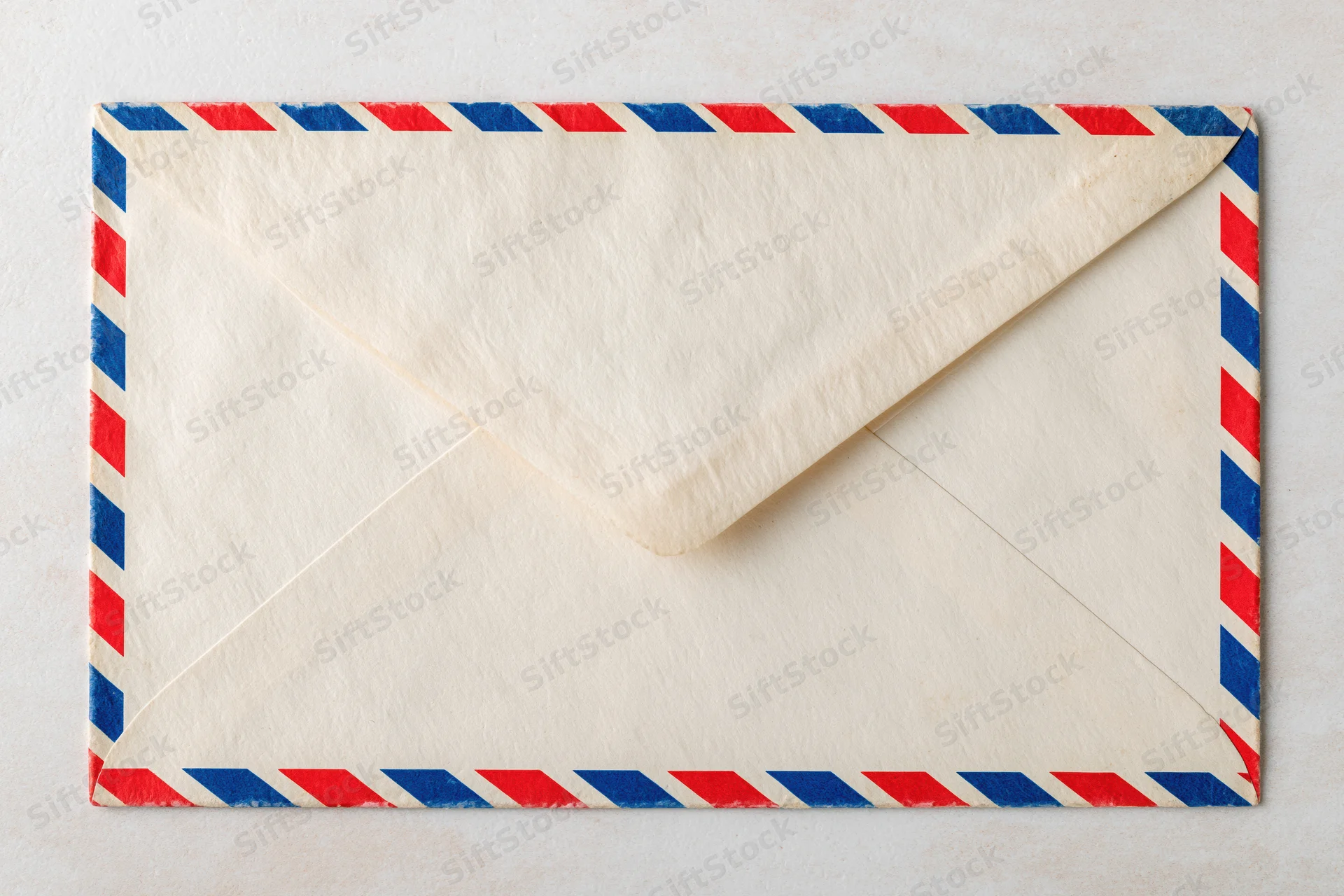Vintage airmail envelope with red and blue striped border lying flat on white surface