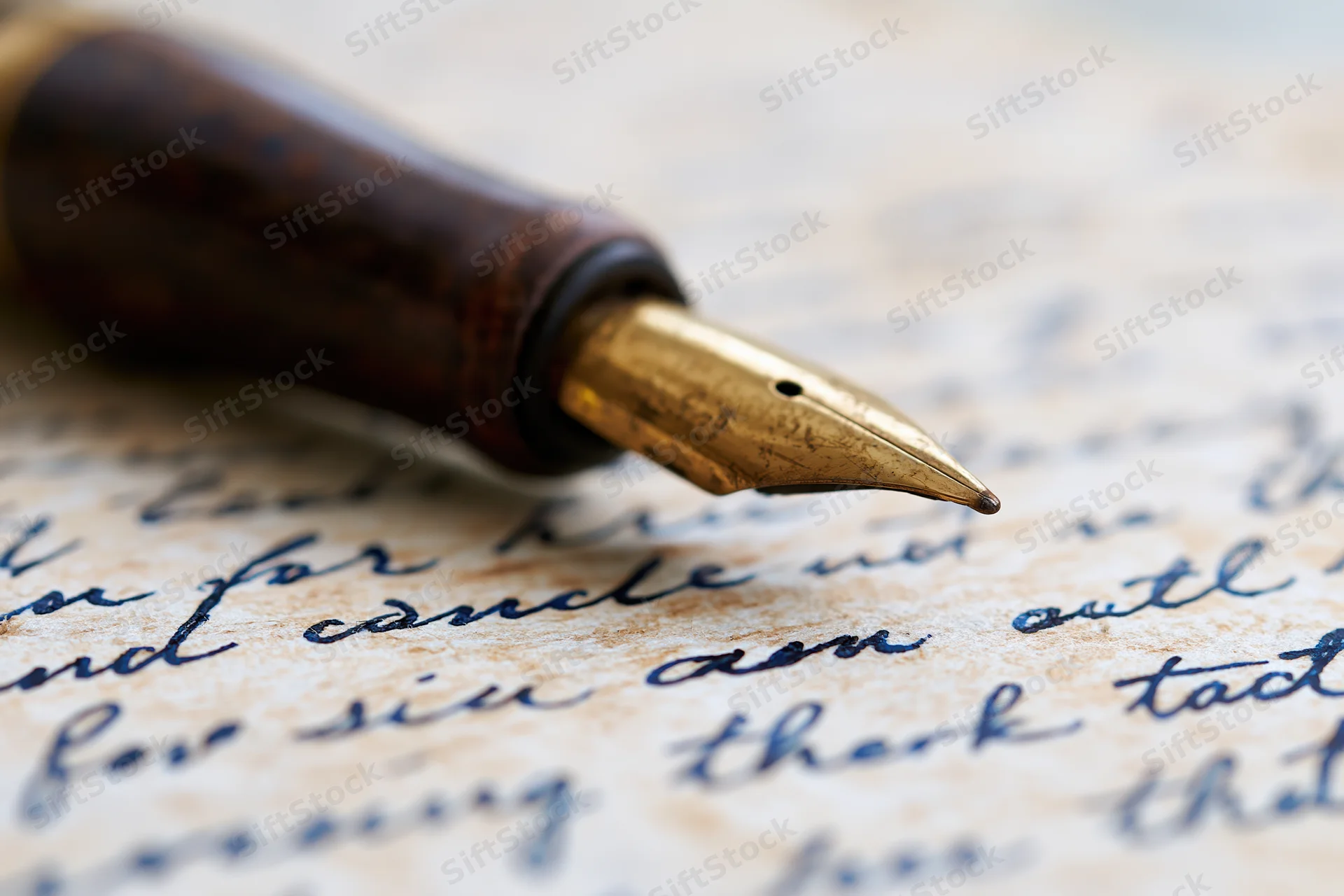 Vintage brass-nibbed fountain pen resting on handwritten letter with cursive script
